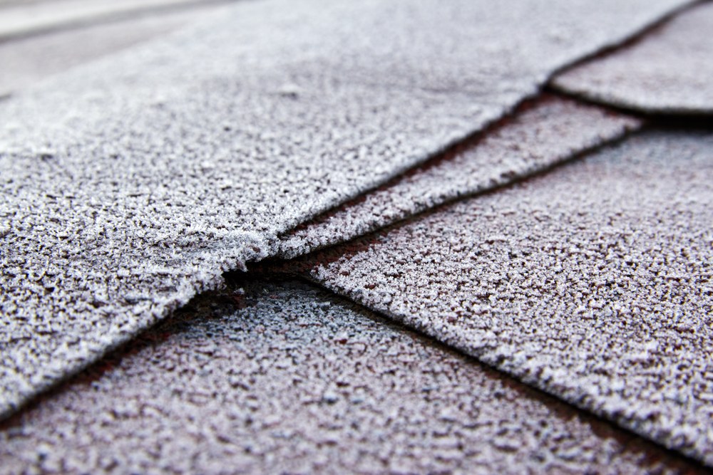 Frost-covered asphalt shingles at a roof valley